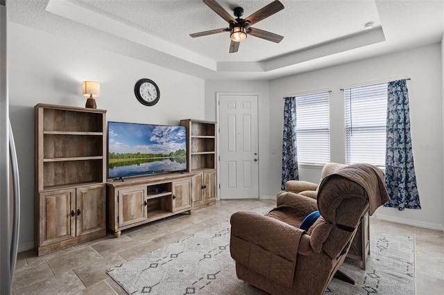 1951 Partin Terrace Rd, Kissimmee, FL 34744 - living area featuring a tray ceiling, a textured ceiling, baseboards, a ceiling fan, and light stone finish floors