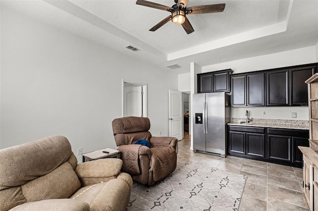1951 Partin Terrace Rd, Kissimmee, FL 34744 - living area with a ceiling fan, a raised ceiling, a textured ceiling, and bar with sink