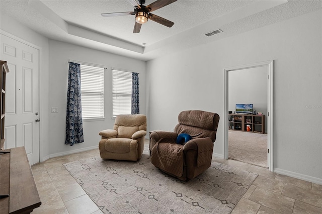 1951 Partin Terrace Rd, Kissimmee, FL 34744 - living area featuring a textured ceiling, a ceiling fan, baseboards, and a tray ceiling