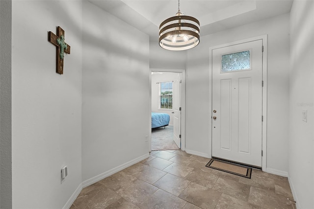1951 Partin Terrace Rd, Kissimmee, FL 34744 - entryway featuring baseboards, a chandelier, stone finish flooring, and a tray ceiling
