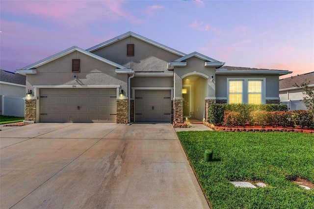 1951 Partin Terrace Rd, Kissimmee, FL 34744 - view of front of house featuring stucco siding, an attached garage, concrete driveway, stone siding, and a lawn