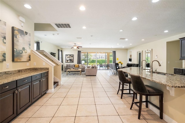 7616 Brookhurst Ln, Kissimmee, FL 34747 - kitchen with a sink, a breakfast bar area, recessed lighting, open floor plan, and light tile patterned flooring