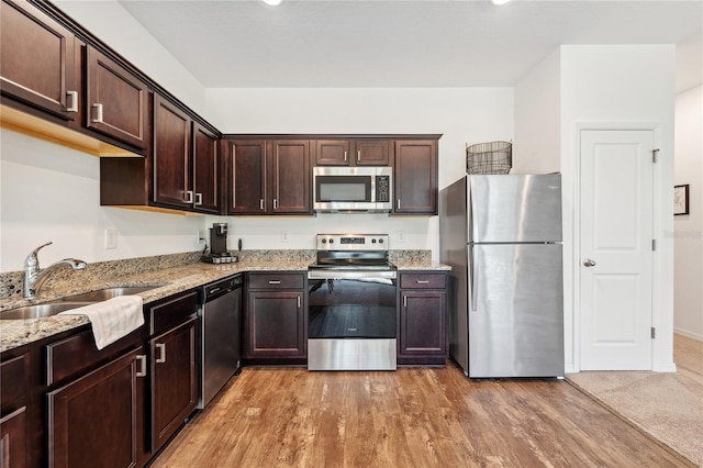 955 Grandin St, Davenport, FL 33837 - kitchen featuring appliances with stainless steel finishes, a sink, dark brown cabinets, and light stone counters