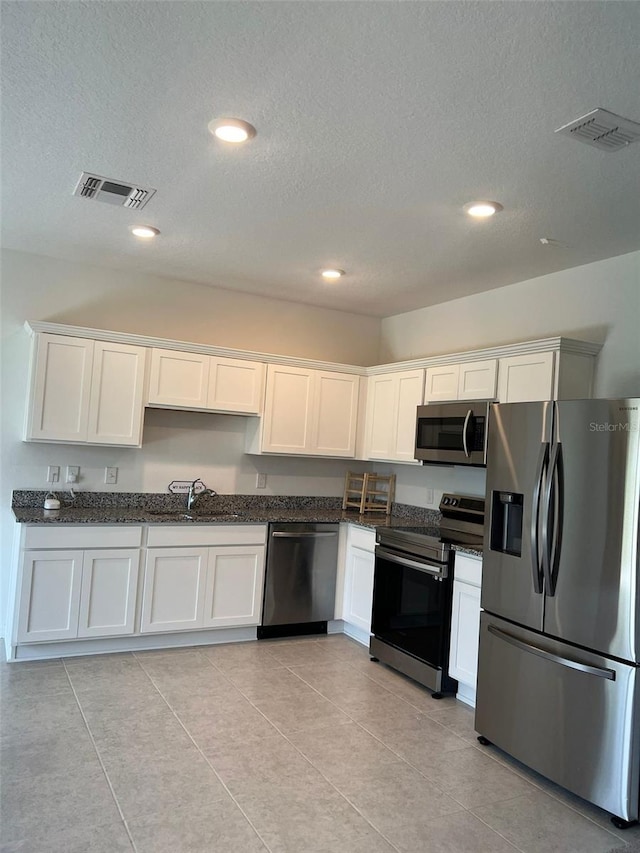 254 Mandovi St, Davenport, FL 33837 - kitchen featuring appliances with stainless steel finishes, white cabinetry, dark stone counters, a textured ceiling, and a sink
