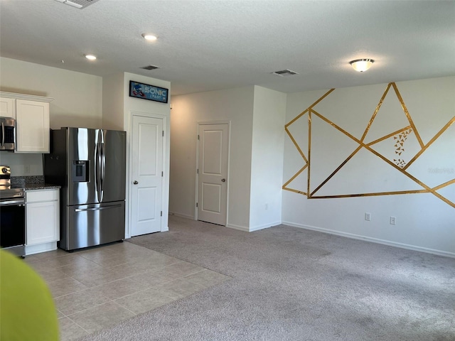 254 Mandovi St, Davenport, FL 33837 - kitchen featuring appliances with stainless steel finishes, white cabinets, light colored carpet, baseboards, and a textured ceiling