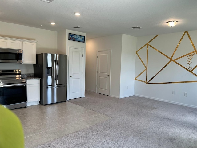 254 Mandovi St, Davenport, FL 33837 - kitchen with appliances with stainless steel finishes, white cabinetry, light colored carpet, baseboards, and a textured ceiling
