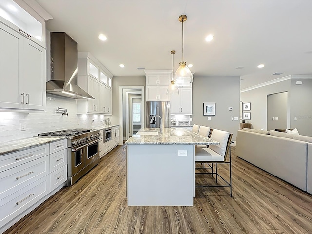 960 Civitas Way, Winter Garden, FL 34787 - kitchen featuring stainless steel appliances, wall chimney range hood, wood finished floors, open floor plan, and decorative backsplash