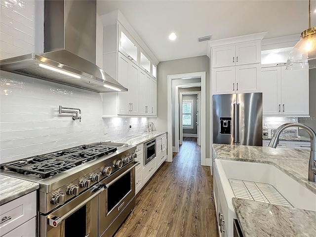 960 Civitas Way, Winter Garden, FL 34787 - kitchen with premium appliances, wall chimney exhaust hood, a sink, white cabinets, and recessed lighting