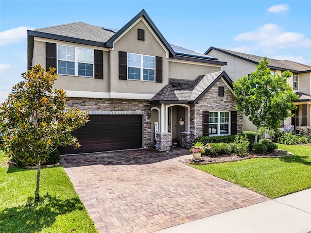 3420 Middlebrook Pl, Harmony, FL 34773 - view of front of property with stucco siding, stone siding, a front yard, decorative driveway, and roof mounted solar panels