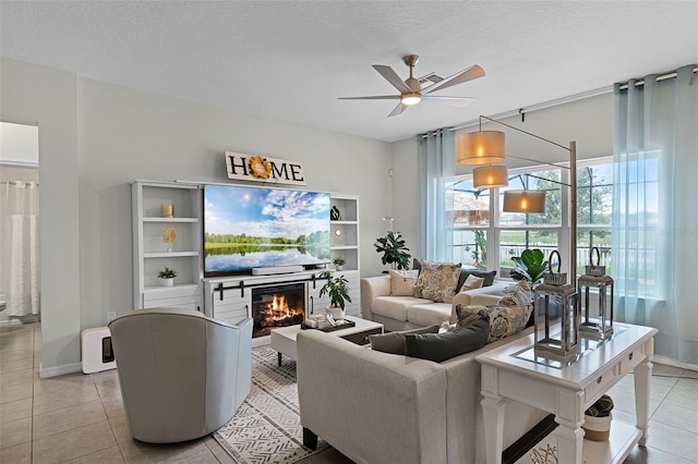 3420 Middlebrook Pl, Harmony, FL 34773 - living room featuring light tile patterned flooring, a ceiling fan, a glass covered fireplace, and a textured ceiling