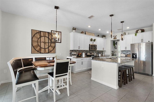 3420 Middlebrook Pl, Harmony, FL 34773 - kitchen with appliances with stainless steel finishes, decorative backsplash, a breakfast bar, a chandelier, and a center island with sink