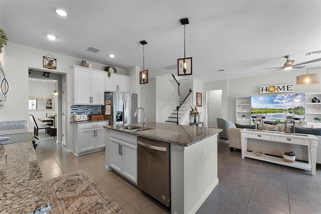 3420 Middlebrook Pl, Harmony, FL 34773 - kitchen featuring appliances with stainless steel finishes, open floor plan, white cabinets, dark stone countertops, and a ceiling fan