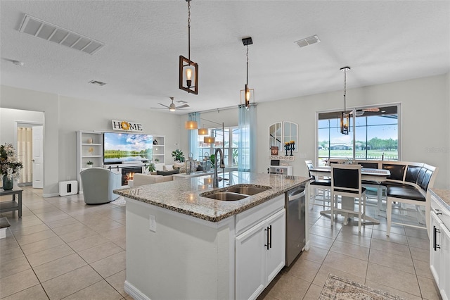 3420 Middlebrook Pl, Harmony, FL 34773 - kitchen featuring stainless steel dishwasher, a ceiling fan, light tile patterned floors, a center island with sink, and white cabinets