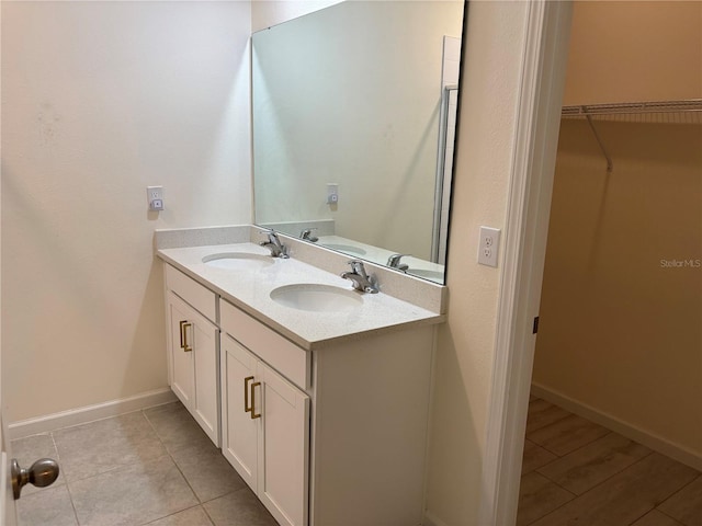 3476 Yarian Dr, Haines City, FL 33844 - bathroom with double vanity, a walk in closet, baseboards, and tile patterned flooring