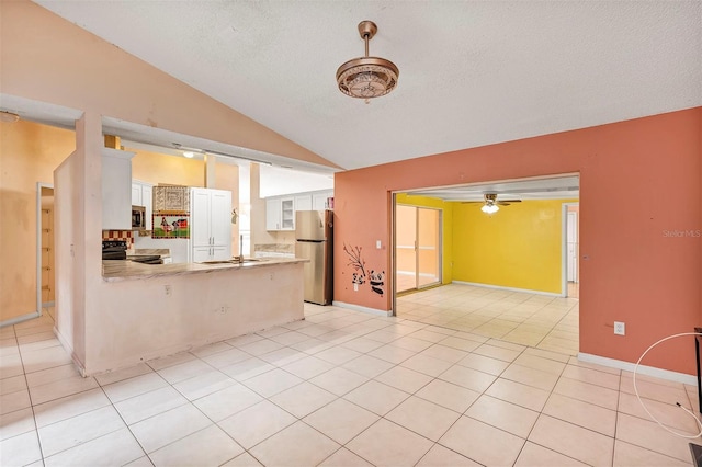 600 Regency Way, Kissimmee, FL 34758 - kitchen featuring freestanding refrigerator, black range with electric stovetop, vaulted ceiling, a peninsula, and white cabinetry
