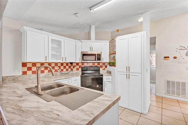 600 Regency Way, Kissimmee, FL 34758 - kitchen featuring stainless steel microwave, black electric range oven, white cabinets, decorative backsplash, and light countertops