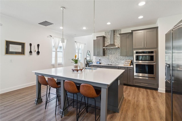 3224 Oxbow Ct, Harmony, FL 34773 - kitchen featuring wall chimney exhaust hood, a sink, appliances with stainless steel finishes, a center island with sink, and wood finished floors