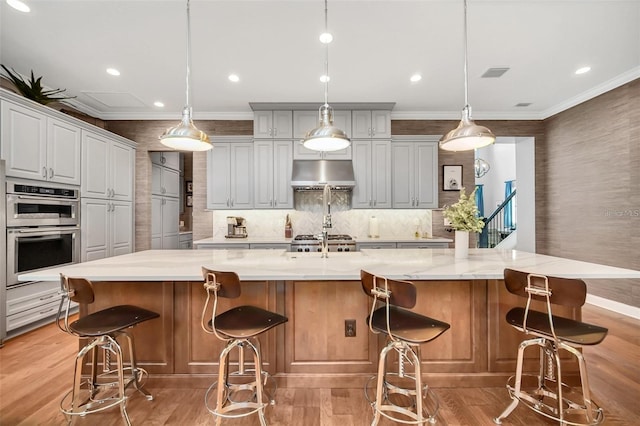 10836 Royal Cypress Way, Orlando, FL 32836 - kitchen featuring under cabinet range hood, double oven, ornamental molding, light wood-style flooring, and a spacious island