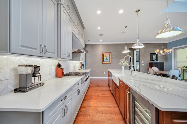 10836 Royal Cypress Way, Orlando, FL 32836 - kitchen featuring stainless steel gas cooktop, a sink, beverage cooler, under cabinet range hood, and light wood-style flooring