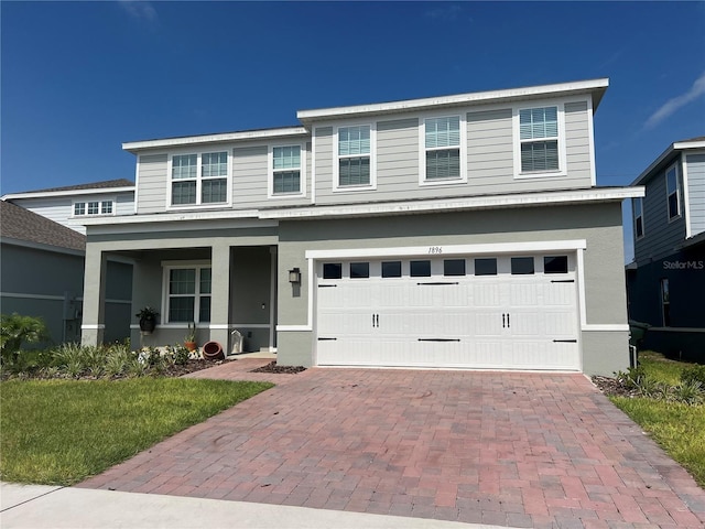 1896 Basenji Dr, Lake Alfred, FL 33850 - view of front facade with a garage, decorative driveway, a porch, stucco siding, and a front yard