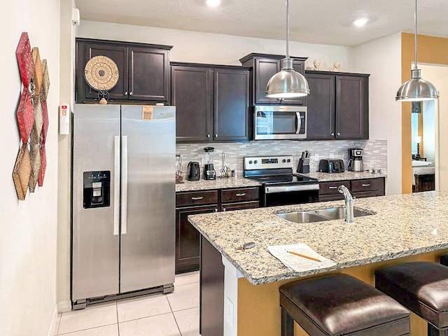 1876 Summer Dr, Davenport, FL 33897 - kitchen with appliances with stainless steel finishes, a sink, light tile patterned floors, a kitchen bar, and backsplash