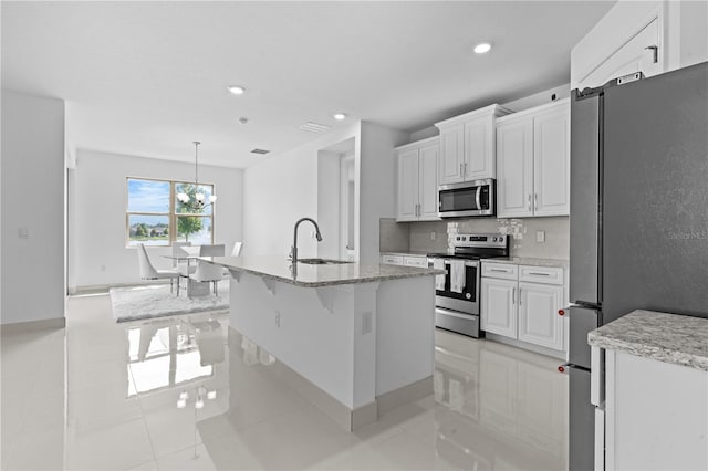 17795 Blazing Star Cir, Clermont, FL 34714 - kitchen with stainless steel appliances, a sink, recessed lighting, white cabinetry, and an island with sink