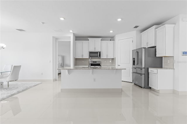 17795 Blazing Star Cir, Clermont, FL 34714 - kitchen with appliances with stainless steel finishes, white cabinetry, recessed lighting, a kitchen bar, and light stone countertops