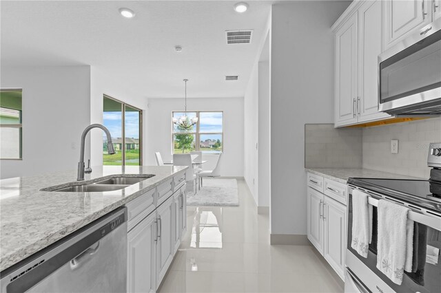 17795 Blazing Star Cir, Clermont, FL 34714 - kitchen with stainless steel appliances, a sink, tasteful backsplash, white cabinets, and light stone countertops