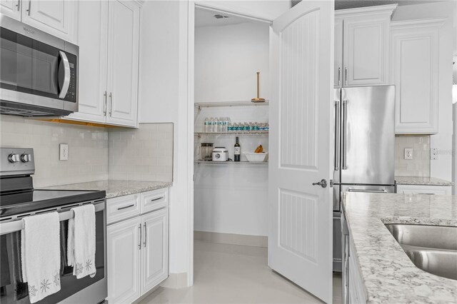 17795 Blazing Star Cir, Clermont, FL 34714 - kitchen featuring appliances with stainless steel finishes, white cabinetry, tasteful backsplash, and light stone counters