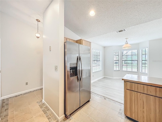 5452 Higgins Way, Orlando, FL 32808 - kitchen featuring stainless steel refrigerator with ice dispenser, a textured ceiling, light tile patterned floors, pendant lighting, and baseboards