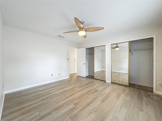5452 Higgins Way, Orlando, FL 32808 - unfurnished bedroom with multiple closets, light wood finished floors, baseboards, a textured ceiling, and ceiling fan
