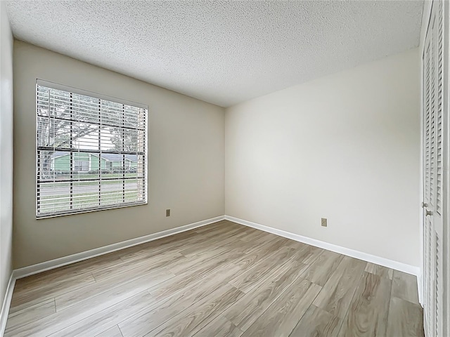 5452 Higgins Way, Orlando, FL 32808 - unfurnished bedroom with light wood finished floors, a textured ceiling, and baseboards