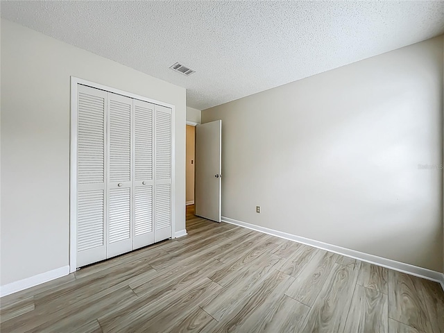 5452 Higgins Way, Orlando, FL 32808 - unfurnished bedroom with light wood finished floors, a closet, baseboards, and a textured ceiling