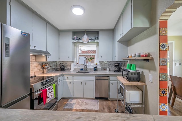 2601 Upton St S, Gulfport, FL 33711 - kitchen featuring stainless steel appliances, range hood, a sink, light wood-style floors, and tasteful backsplash