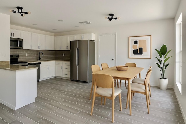 4546 Ontario Dr, New Port Richey, FL 34652 - kitchen with appliances with stainless steel finishes, wood finish floors, white cabinetry, tasteful backsplash, and baseboards