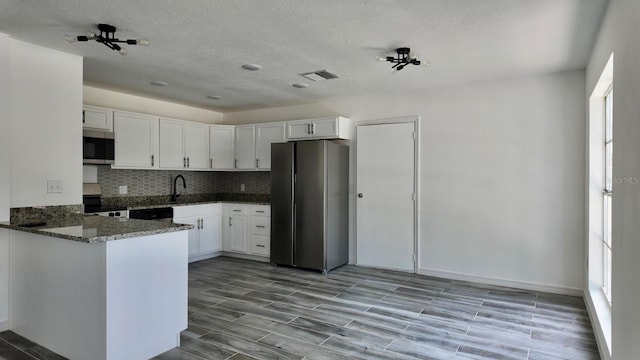 4546 Ontario Dr, New Port Richey, FL 34652 - kitchen with stainless steel appliances, dark stone counters, white cabinetry, backsplash, and a peninsula
