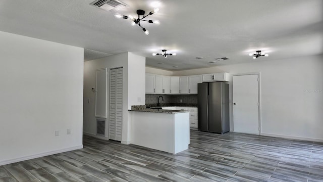4546 Ontario Dr, New Port Richey, FL 34652 - kitchen featuring freestanding refrigerator, white cabinetry, decorative backsplash, wood finished floors, and a peninsula