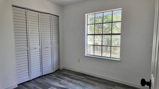 4546 Ontario Dr, New Port Richey, FL 34652 - unfurnished bedroom featuring multiple windows, a closet, baseboards, and wood finish floors