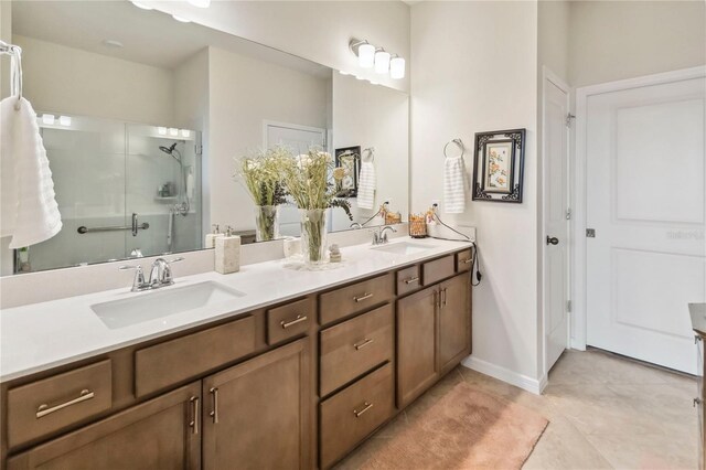 bathroom with double vanity, a shower stall, tile patterned floors, and baseboards