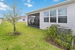 view of green lawn with a sunroom and central AC unit