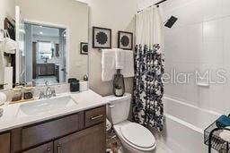 full bath with toilet, vanity, and shower / bathtub combination with curtain