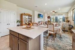 kitchen featuring a kitchen island, light countertops, recessed lighting, dark brown cabinets, and light tile patterned floors