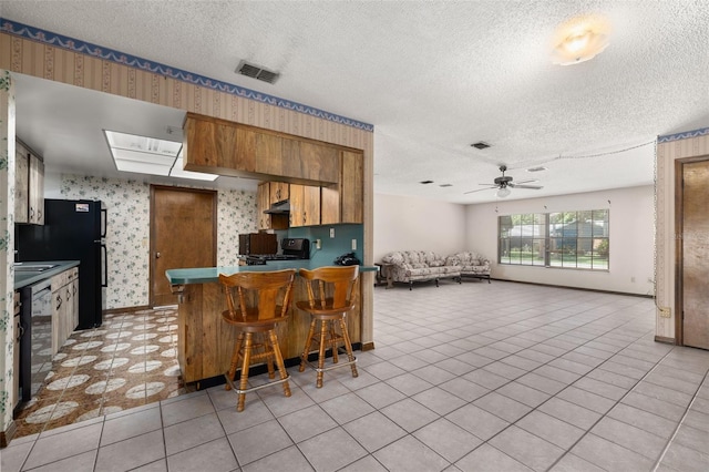 4307 Oak Ct, Saint Cloud, FL 34769 - kitchen featuring wallpapered walls, a textured ceiling, a ceiling fan, a peninsula, and stove