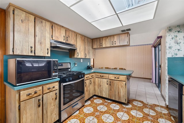 4307 Oak Ct, Saint Cloud, FL 34769 - kitchen with stainless steel range with gas cooktop, under cabinet range hood, black microwave, a peninsula, and wallpapered walls