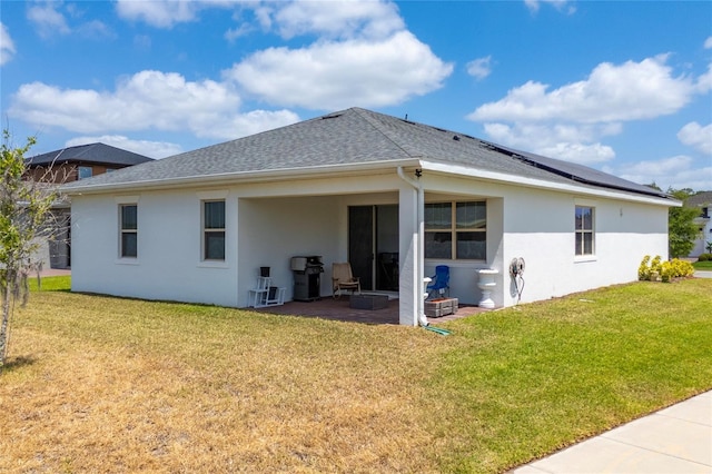 6651 Syreeta Ln, Harmony, FL 34773 - back of property with stucco siding, a yard, roof mounted solar panels, a patio, and a shingled roof
