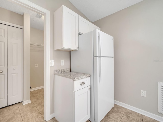 3274 Hunters Chase Loop, Kissimmee, FL 34743 - kitchen with freestanding refrigerator, light tile patterned floors, white cabinets, and baseboards