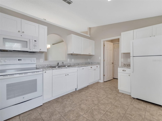 3274 Hunters Chase Loop, Kissimmee, FL 34743 - kitchen featuring white appliances, a sink, white cabinets, arched walkways, and light stone counters