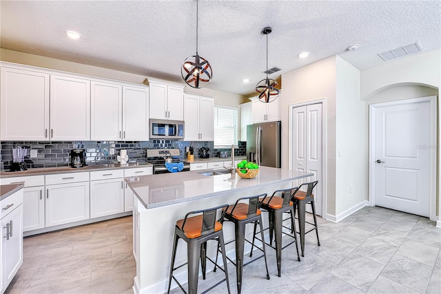 8974 Cabot Cliffs Dr, Davenport, FL 33896 - kitchen featuring appliances with stainless steel finishes, a sink, decorative backsplash, a kitchen bar, and white cabinets