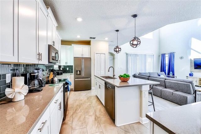 8974 Cabot Cliffs Dr, Davenport, FL 33896 - kitchen featuring stainless steel appliances, a sink, open floor plan, backsplash, and white cabinets