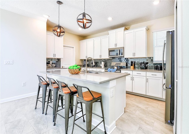 8974 Cabot Cliffs Dr, Davenport, FL 33896 - kitchen with stainless steel appliances, a sink, decorative backsplash, light countertops, and an island with sink